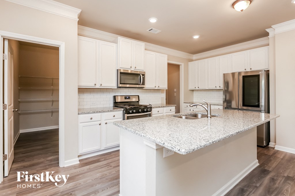 a kitchen with white cabinets and a marble counter top