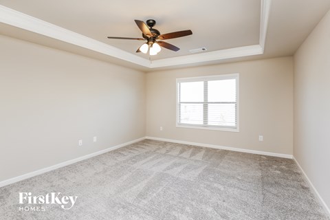 the spacious living room with ceiling fan and carpet