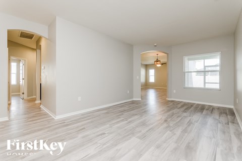 A spacious room with wooden flooring and a large window.