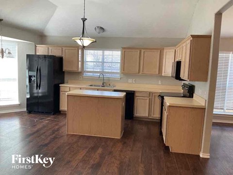 A kitchen with wooden cabinets and a black fridge.