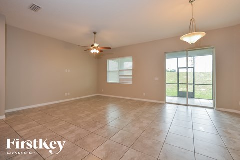 A spacious room with a ceiling fan and sliding glass doors leading to a grassy area.