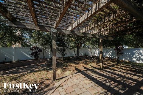 a pergola over a brick patio with trees