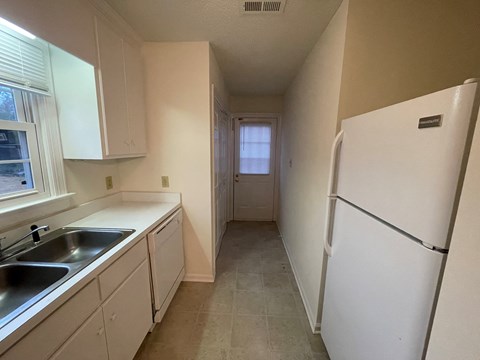 A kitchen with white cabinets and a white refrigerator.