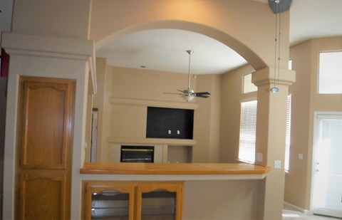 an archway into a living room with a bar and a television