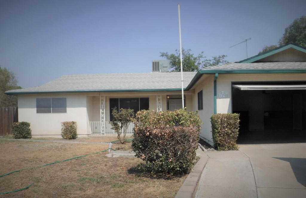 a white house with a green roof and a driveway