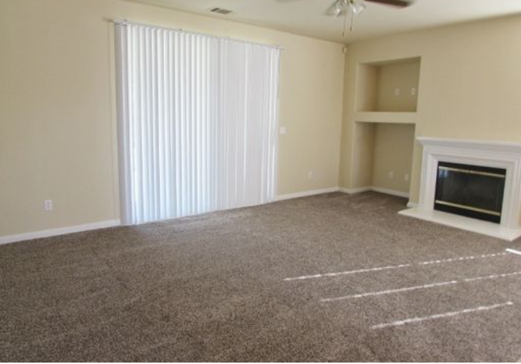 an empty living room with a fireplace and a window