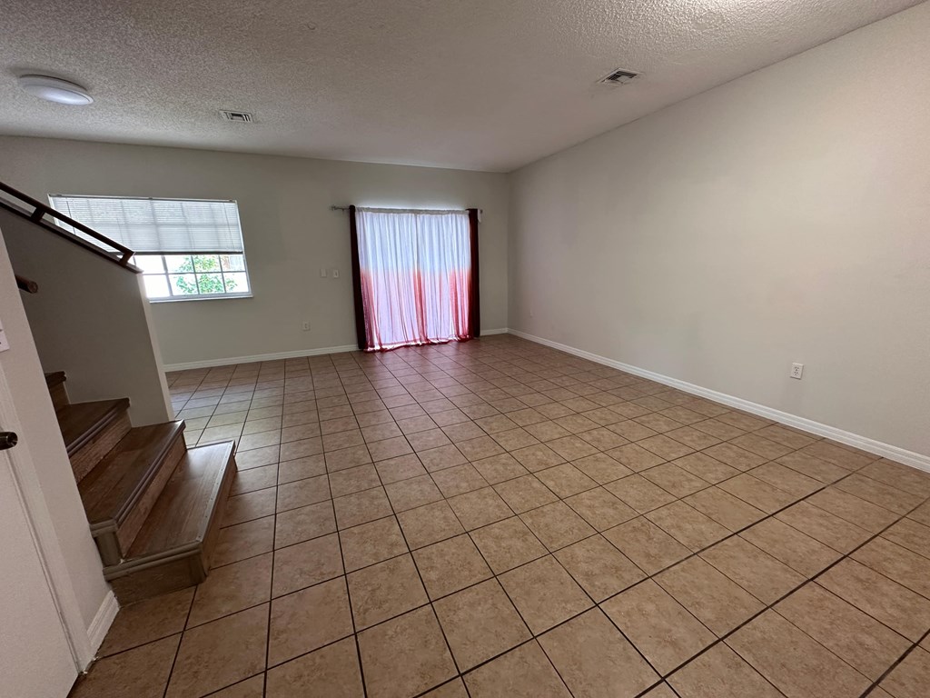 an empty living room with tiled floors and a window
