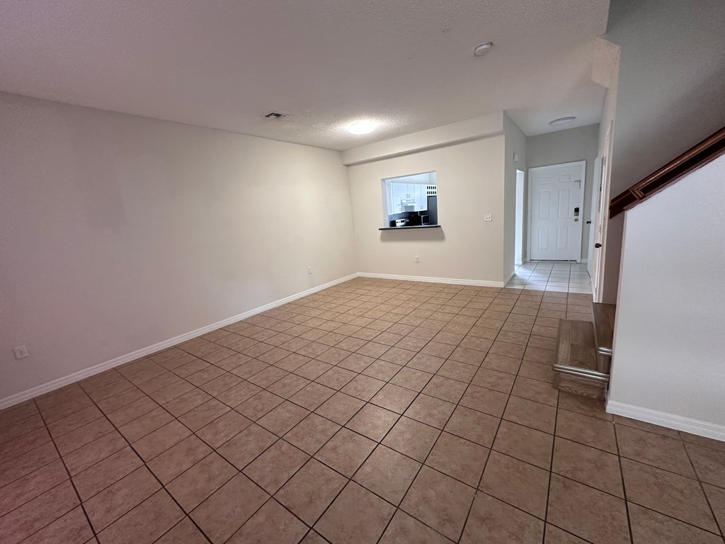 a empty living room with tile flooring and white walls