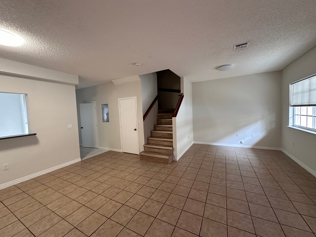 the living room and entryway of an empty house with tile flooring