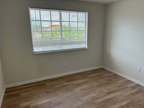 a living room with a large window and wooden floors