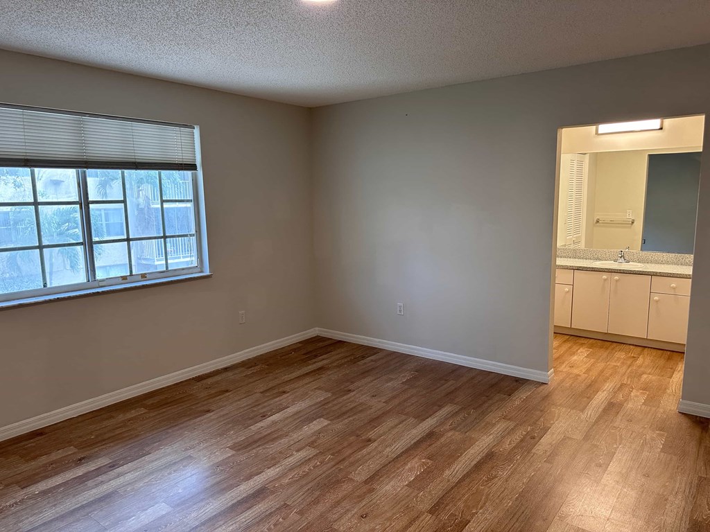 an empty living room with wood flooring and a window