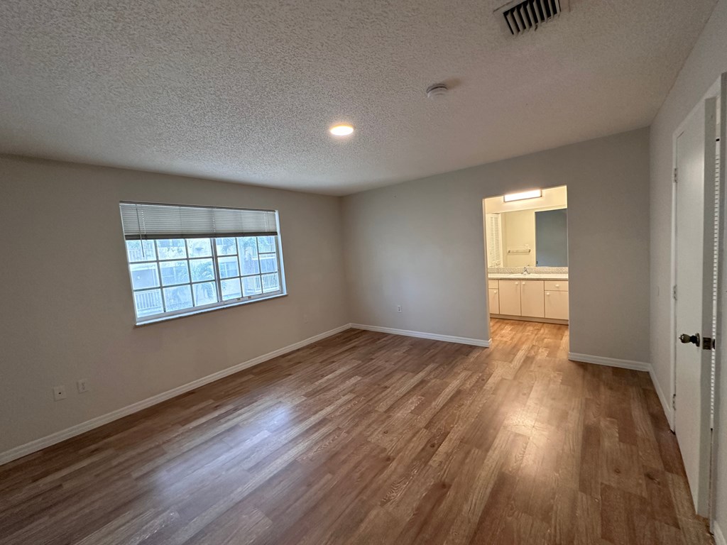 an empty living room with wood floors and a window