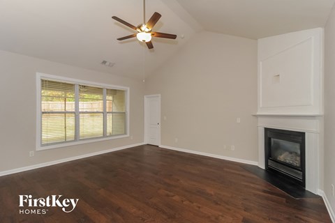 the living room of a home with a fireplace and a ceiling fan