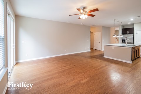 A spacious room with wooden floors and a ceiling fan.