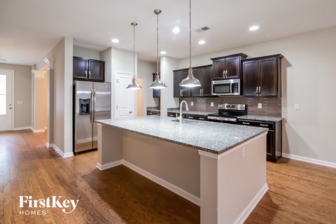 A modern kitchen with a granite countertop and stainless steel appliances.