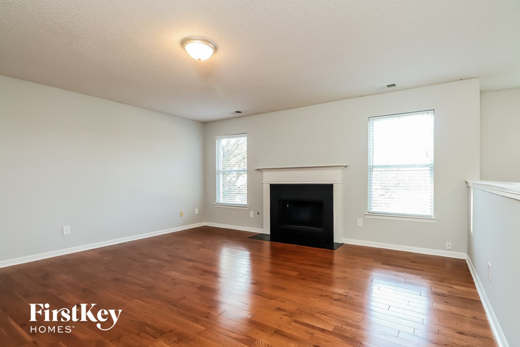the living room with wood floors and a fireplace