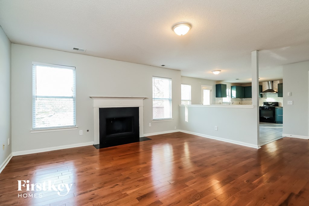 an empty living room with wood floors and a fireplace
