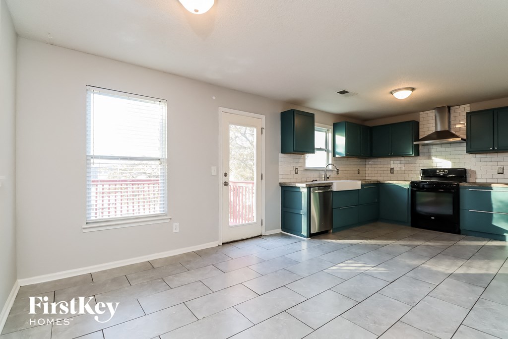 an empty kitchen with green cabinets and a door to a balcony