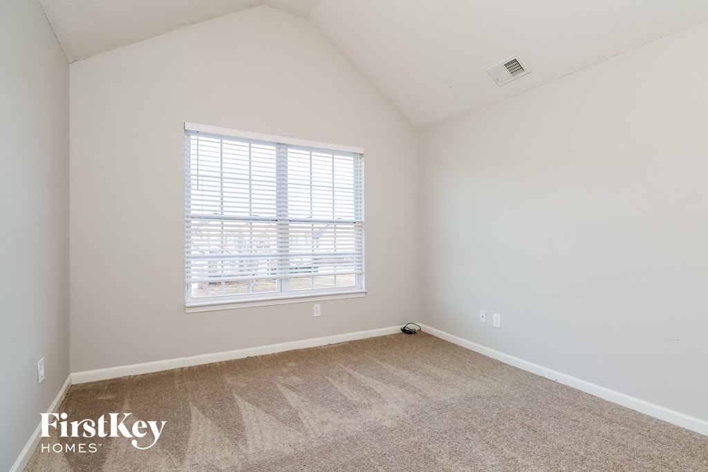 a bedroom with white walls and carpet and a window