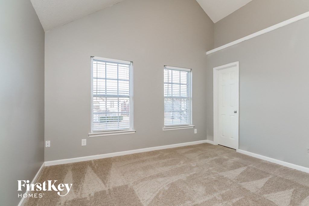 a spacious living room with two windows and a door