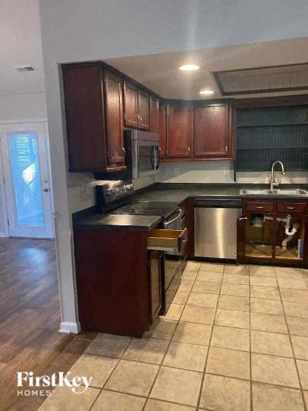 A kitchen with wooden cabinets and a stainless steel dishwasher.