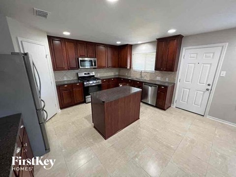 A kitchen with a refrigerator, microwave, oven, and a sink.