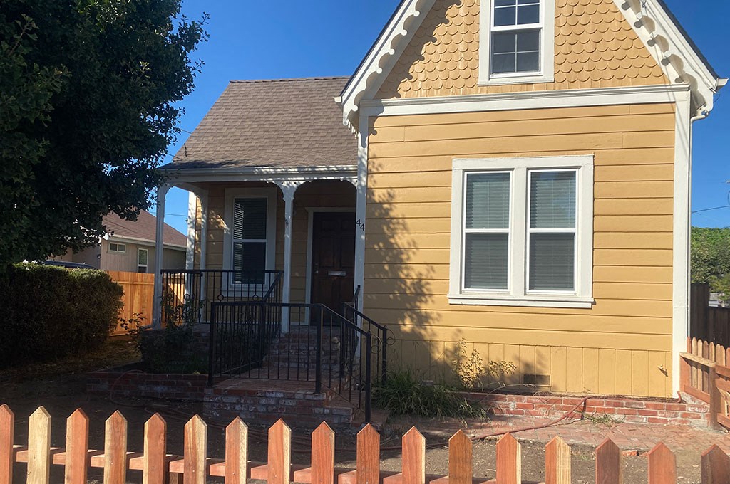 a yellow house with a fence in front of it