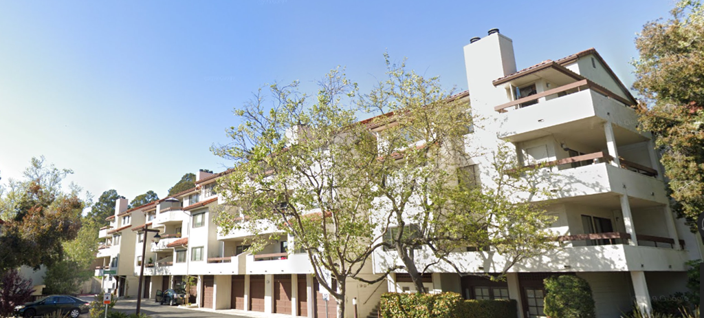 an apartment building on a city street with trees