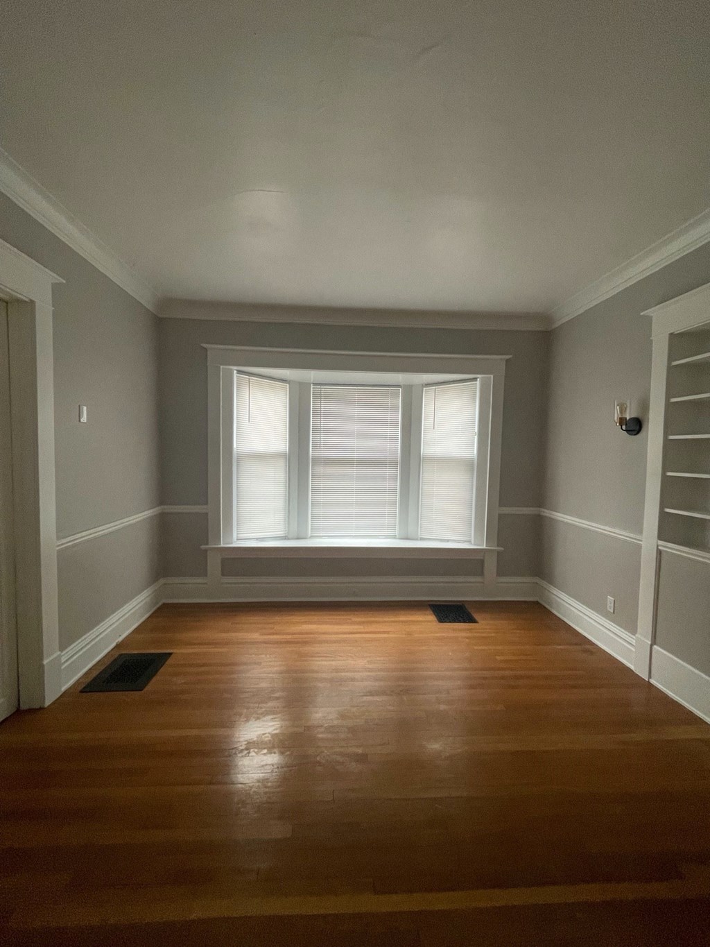 an empty room with a window and wooden floors