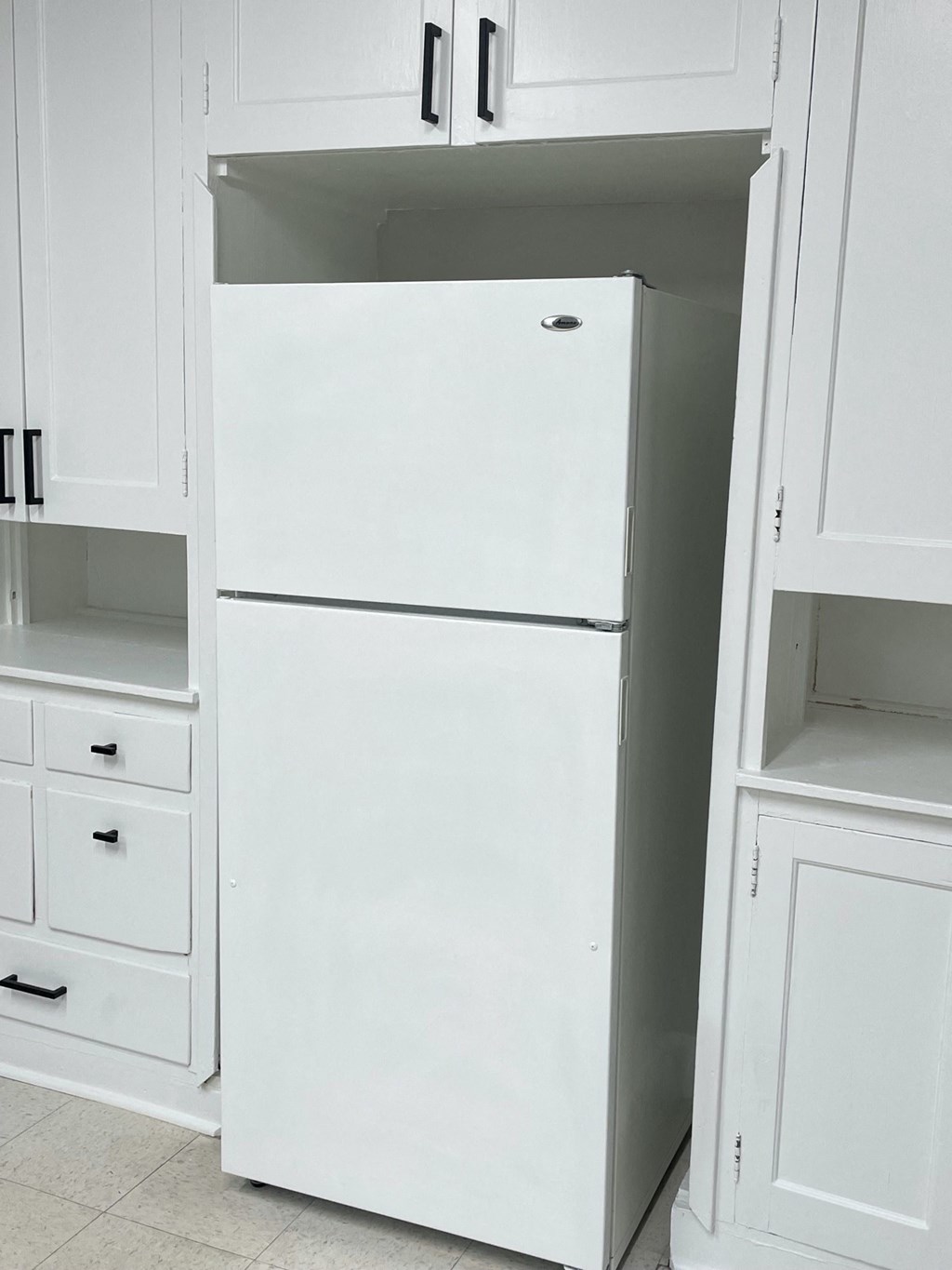 an open refrigerator in a kitchen with white cabinets