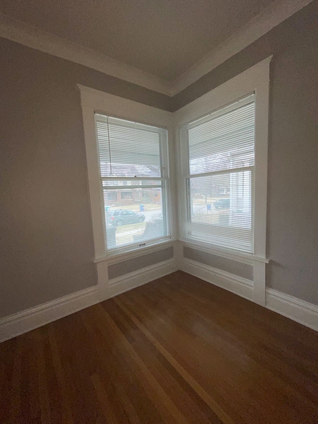 an empty room with three windows and a wooden floor