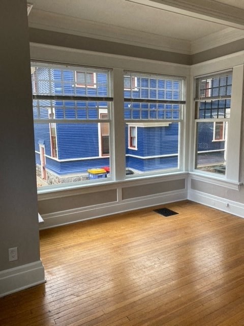 a living room with three windows and a wooden floor