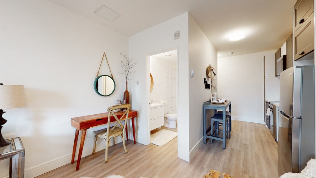 a living room with a desk and a bathroom with a sink