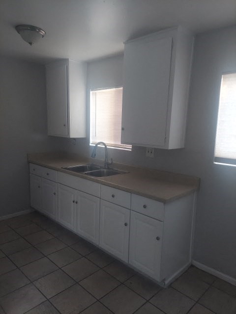 an empty kitchen with white cabinets and a sink