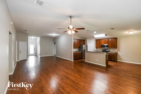 A spacious living room with wood flooring and a ceiling fan.