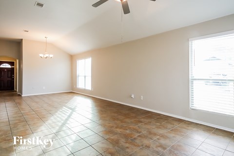 A spacious room with tile flooring and a ceiling fan.