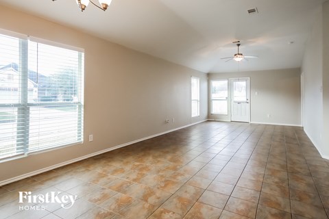 A spacious room with tile flooring and a ceiling fan.