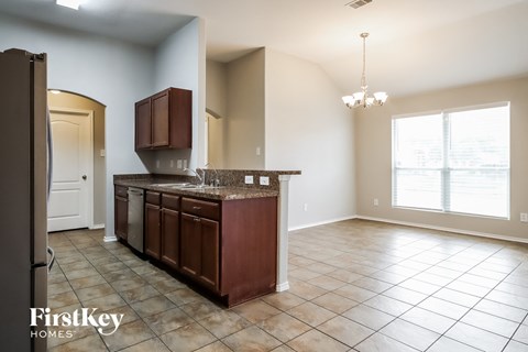 A kitchen with brown cabinets and a tiled floor.