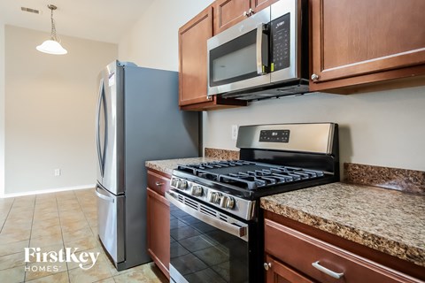 A kitchen with a stove, refrigerator, and microwave.