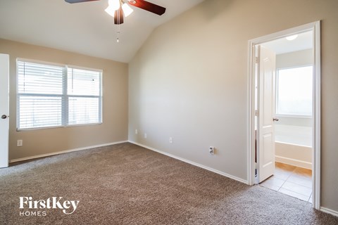 A room with a carpet floor and a ceiling fan.