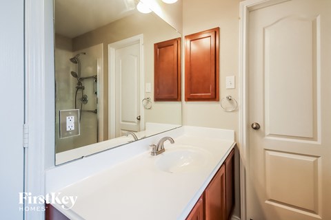 A bathroom with a white counter top and a mirror above the sink.