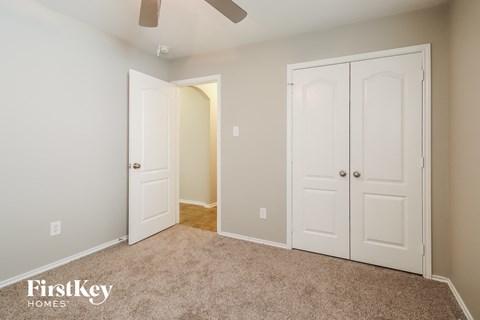 A room with a carpeted floor and a ceiling fan.