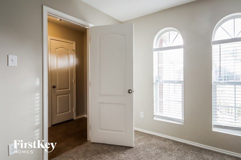 A white door is open to a hallway with a carpeted floor.