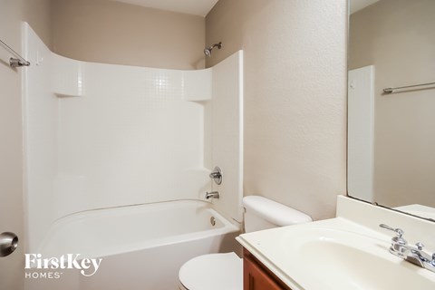 A white bathroom with a tub, toilet and sink.
