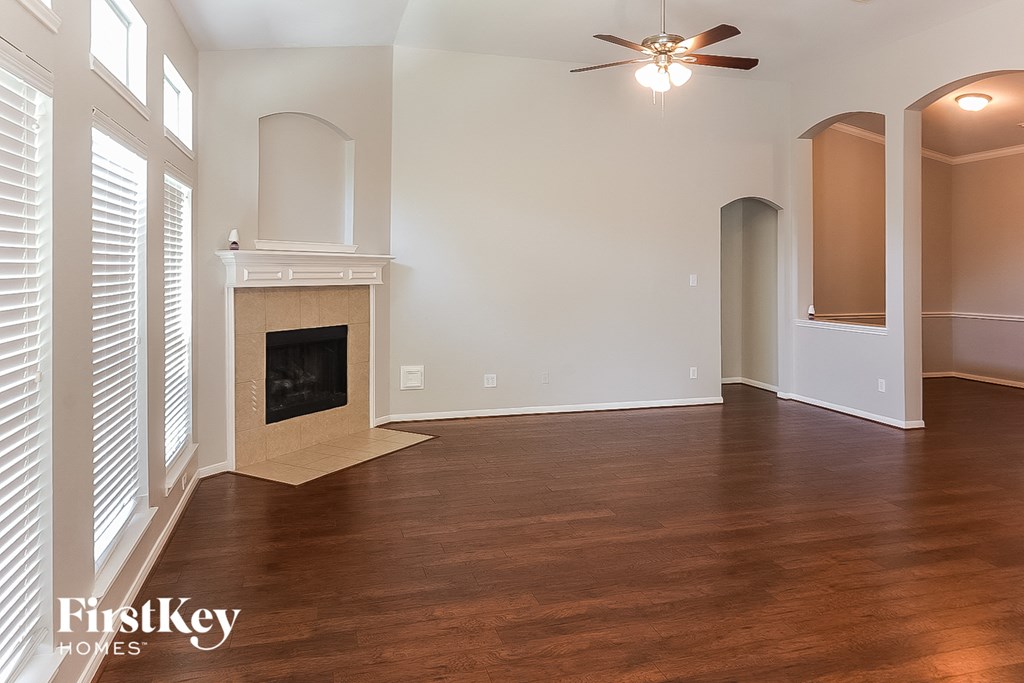 A spacious room with a fireplace and wooden flooring.