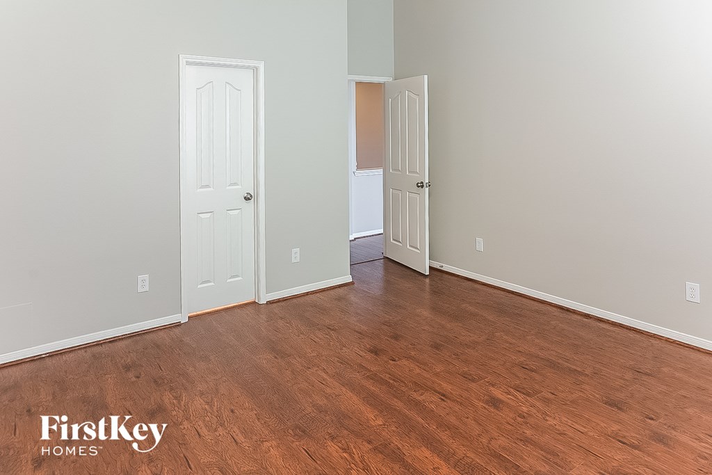 A room with wooden floors and two doors, one of which is open.