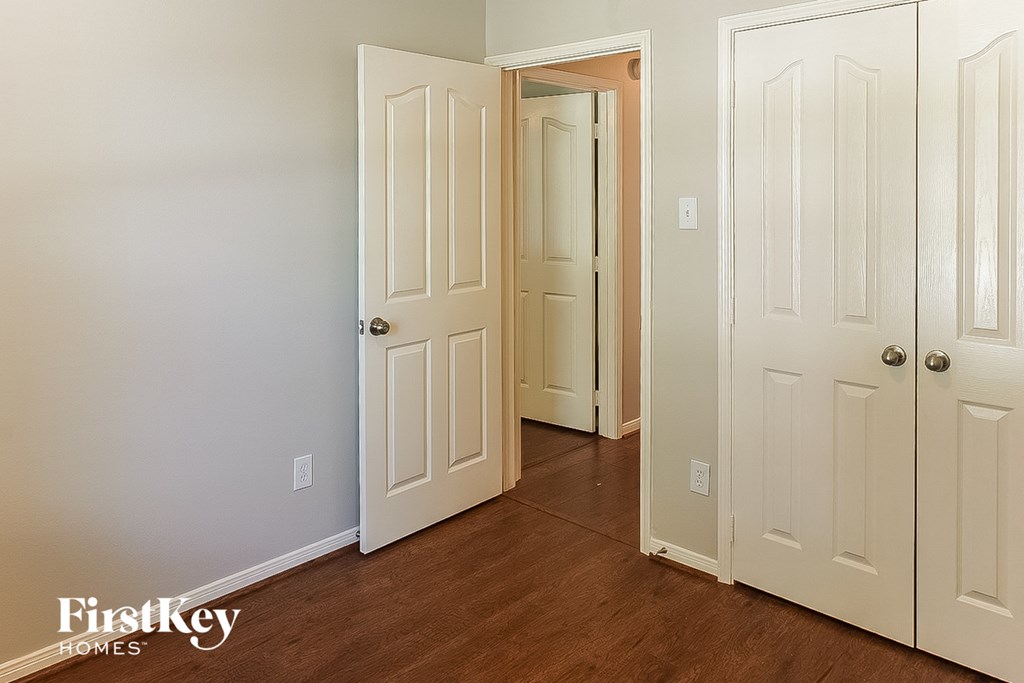 A room with a white door and a wooden floor.