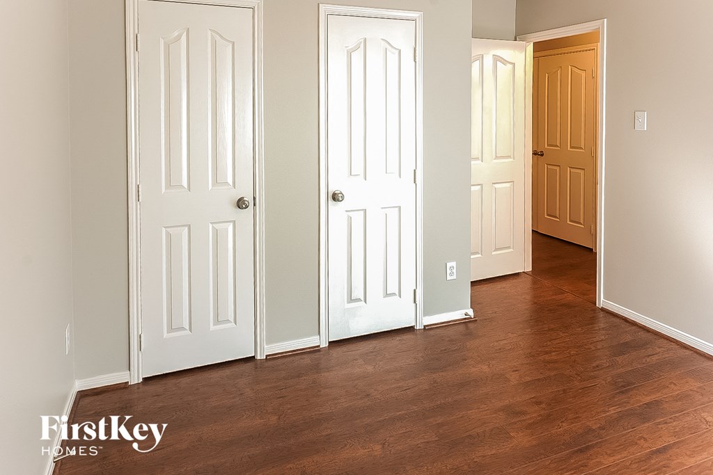 A room with three doors and wooden floors.