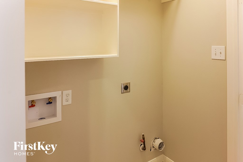 A bathroom with a toilet paper holder and a shelf above it.