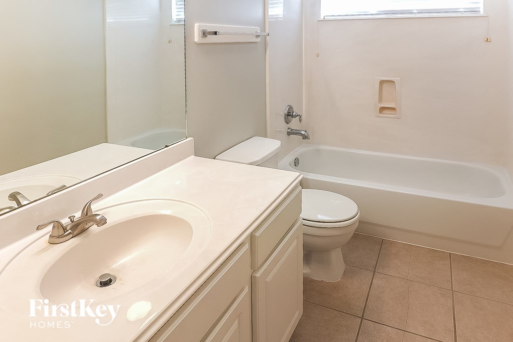 A white bathroom with a sink, toilet and tub.